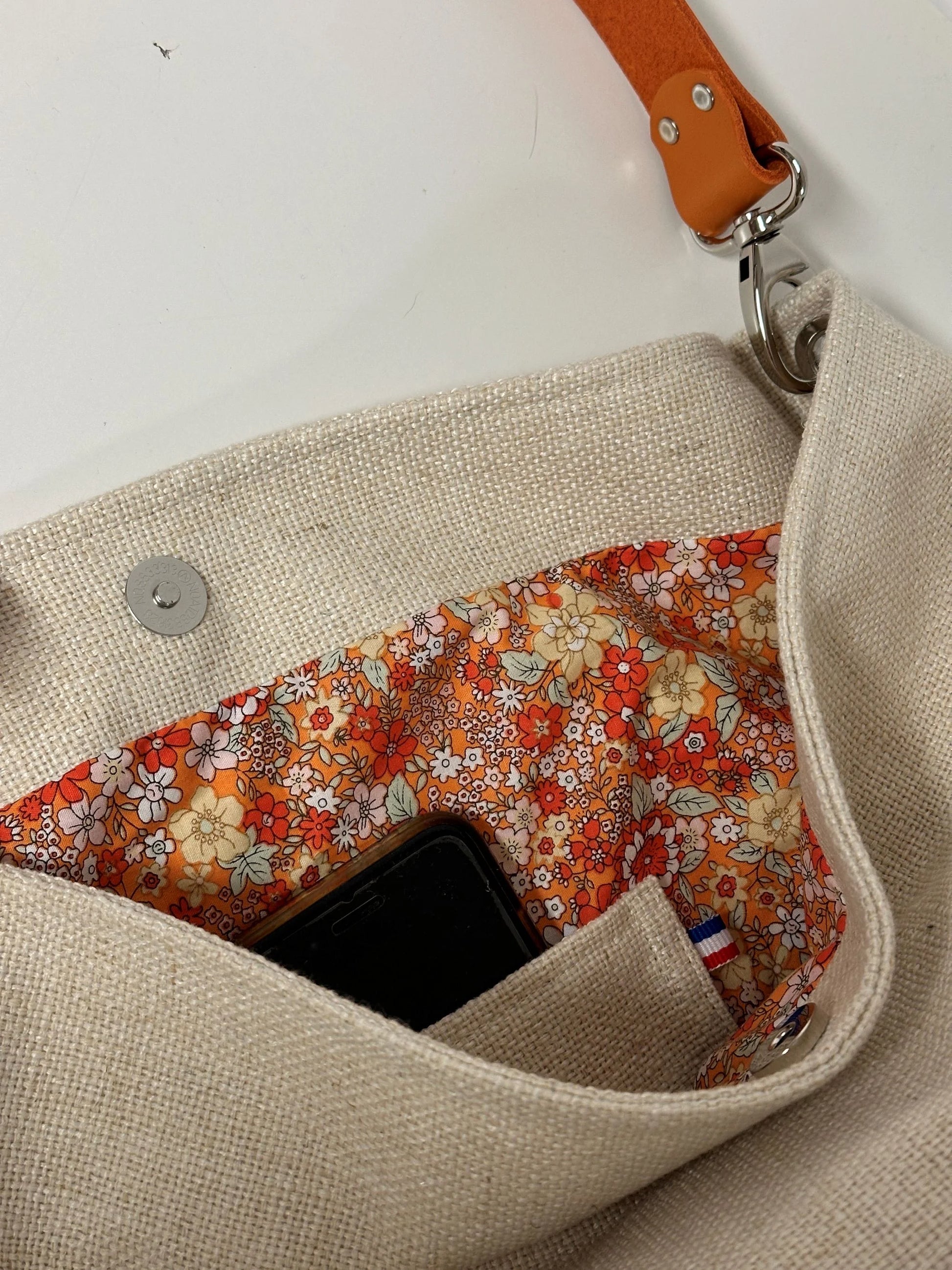 La poche intérieure pour le smartphone, du sac hobo en lin ivoire et son anse en cuir orange.