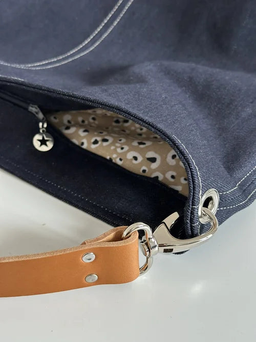 Le sac hobo en toile denim brut avec fermeture éclair.