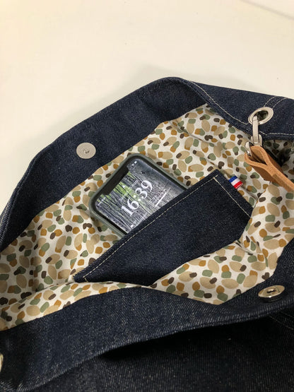 La poche plaquée intérieure du sac hobo en toile denim brut et son anse en cuir .