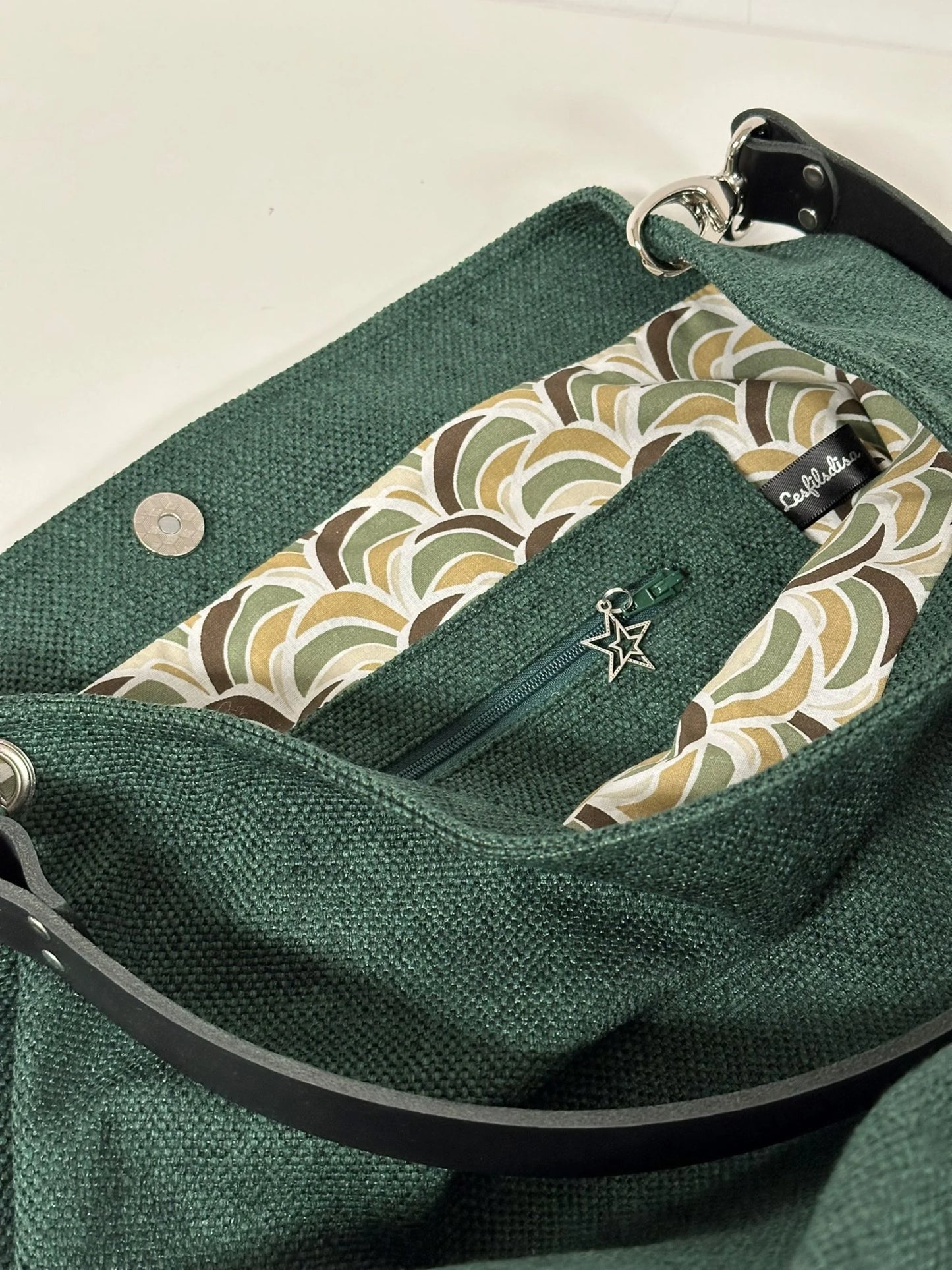 La poche zippée intérieure du sac hobo en toile vert forêt et son anse en cuir .