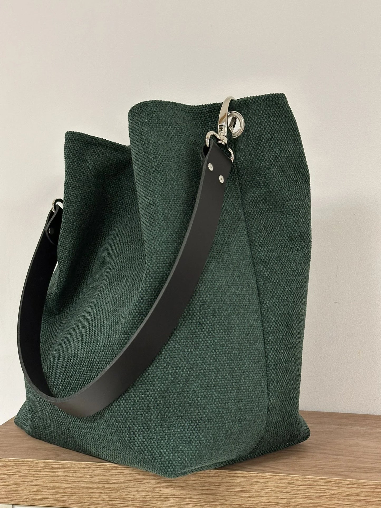 Le sac hobo en toile vert forêt et son anse en cuir noir.