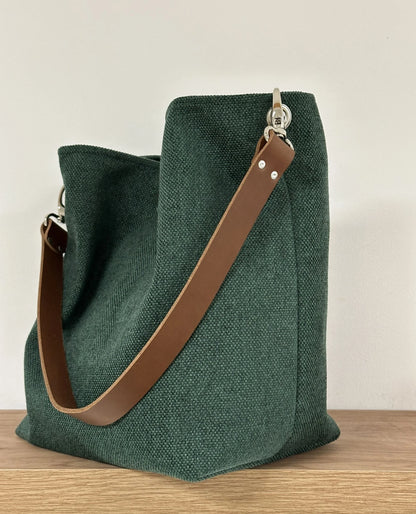 Le sac hobo en toile vert forêt et son anse en cuir marron.