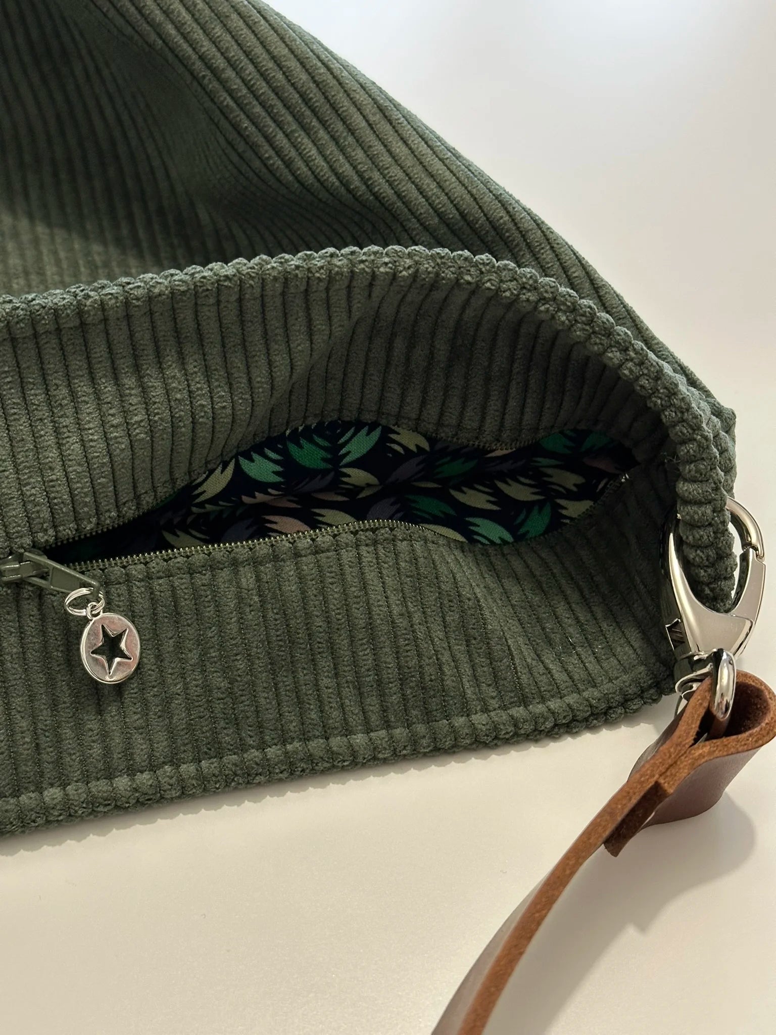 Le sac hobo en velours cotelé vert kaki avec fermeture éclair.