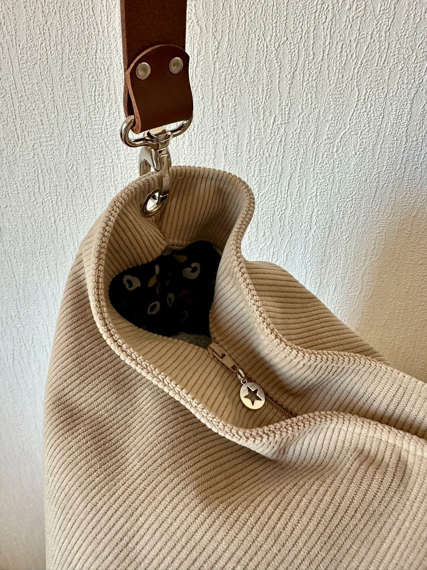 Le sac hobo en velours cotelé beige avec fermeture éclair.