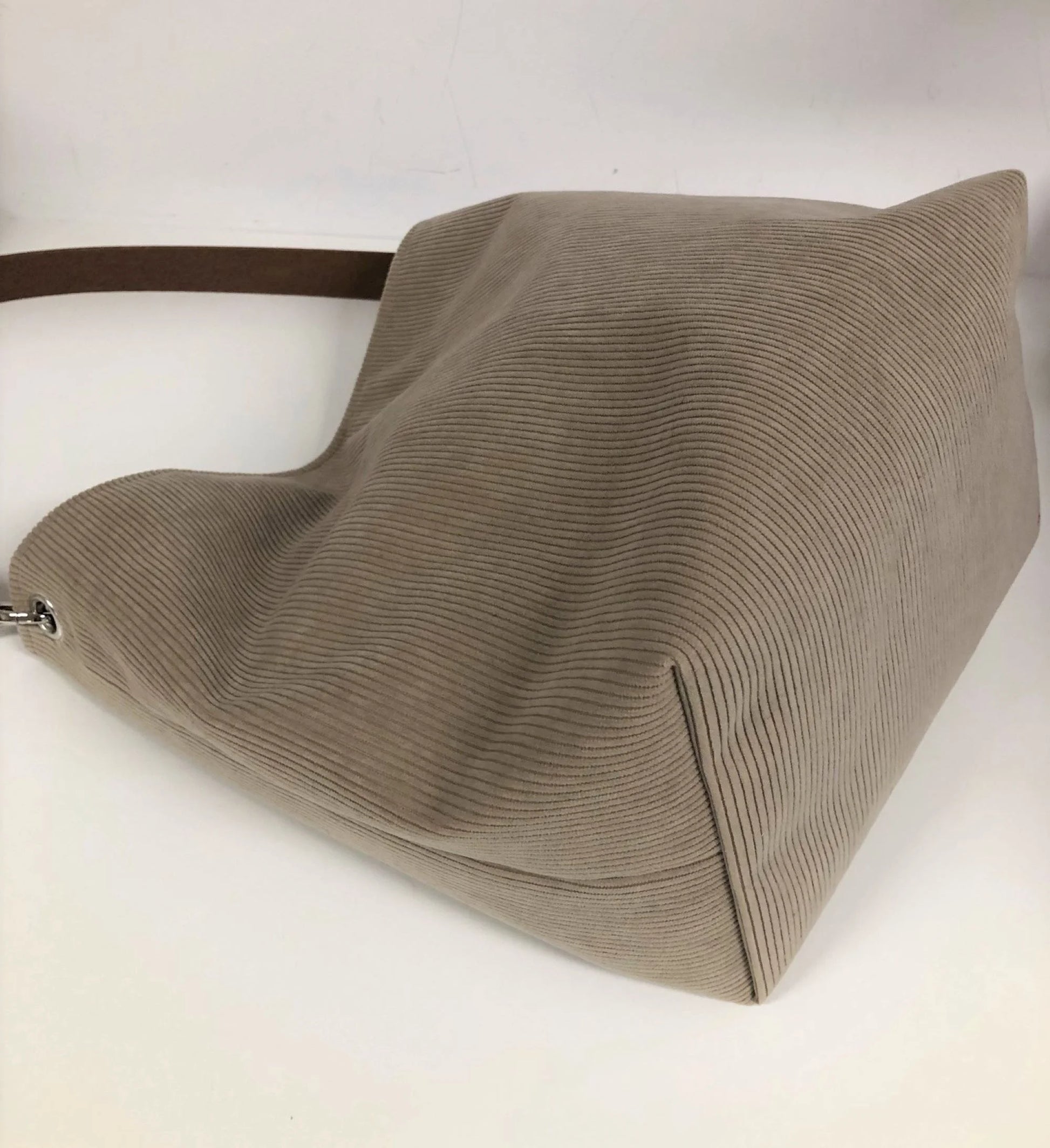 Le fond du sac hobo en velours cotelé beige et son anse en cuir marron.