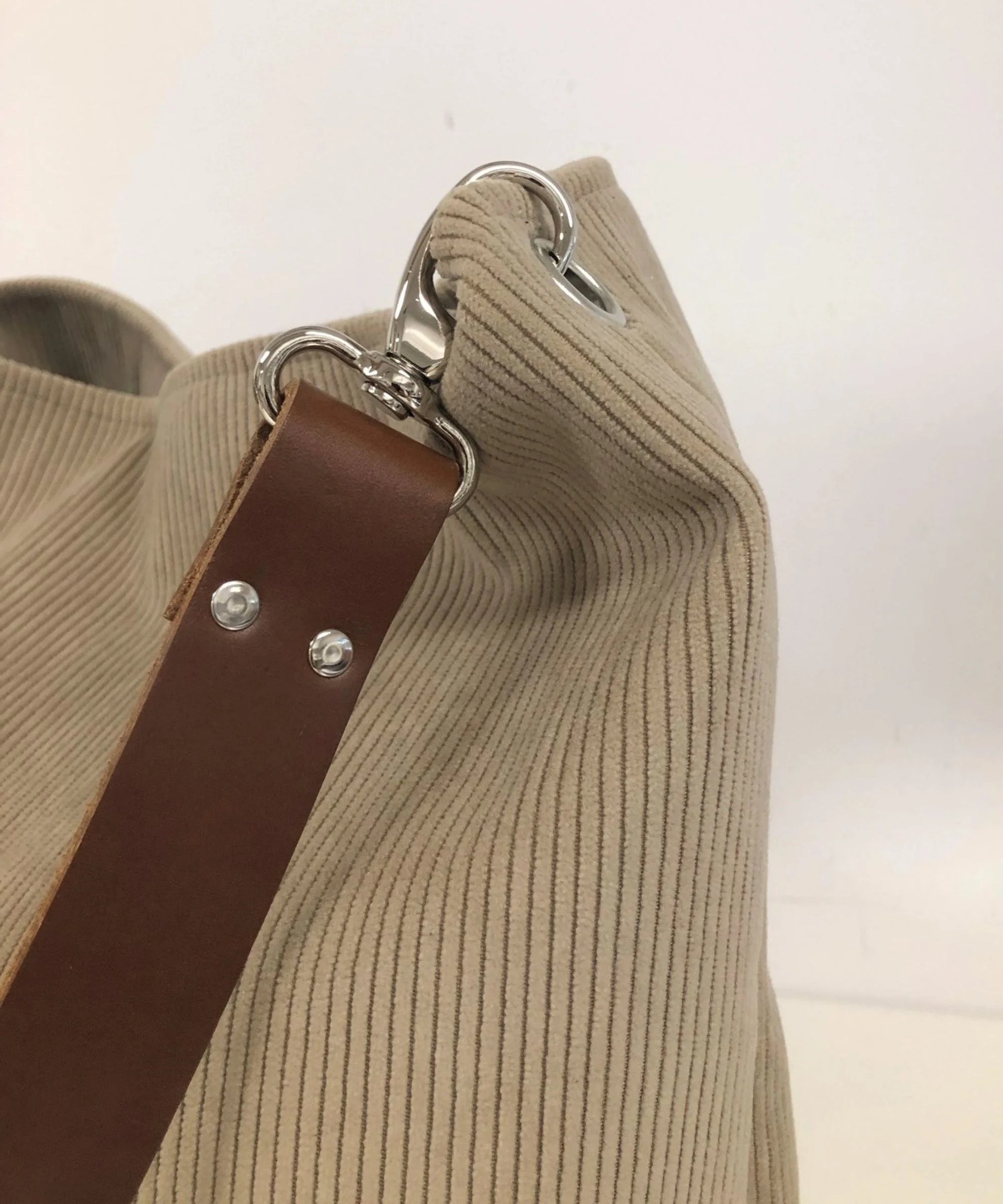 Vue détaillée de l'anse en cuir du sac hobo en velours cotelé beige.