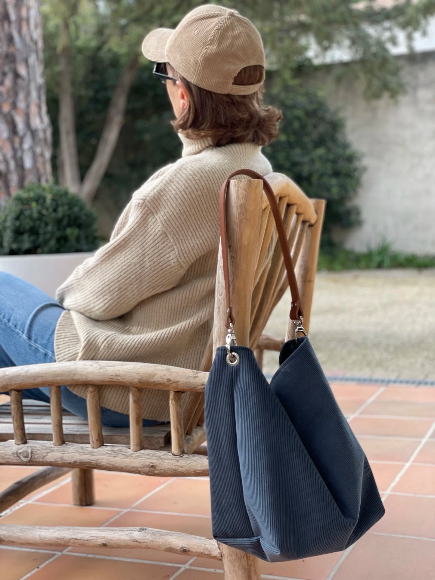 Femme avec le sac hobo en velours cotelé bleu canard et son anse en cuir marron.