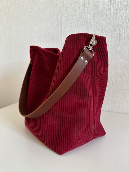 Le sac Hobo en velours cotelé bordeaux, et anse en cuir  marron.