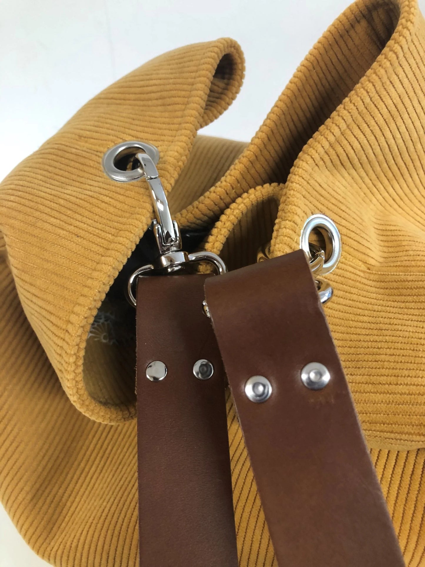 Vue détaillée du sac hobo en velours cotelé jaune moutarde et son anse en cuir marron.