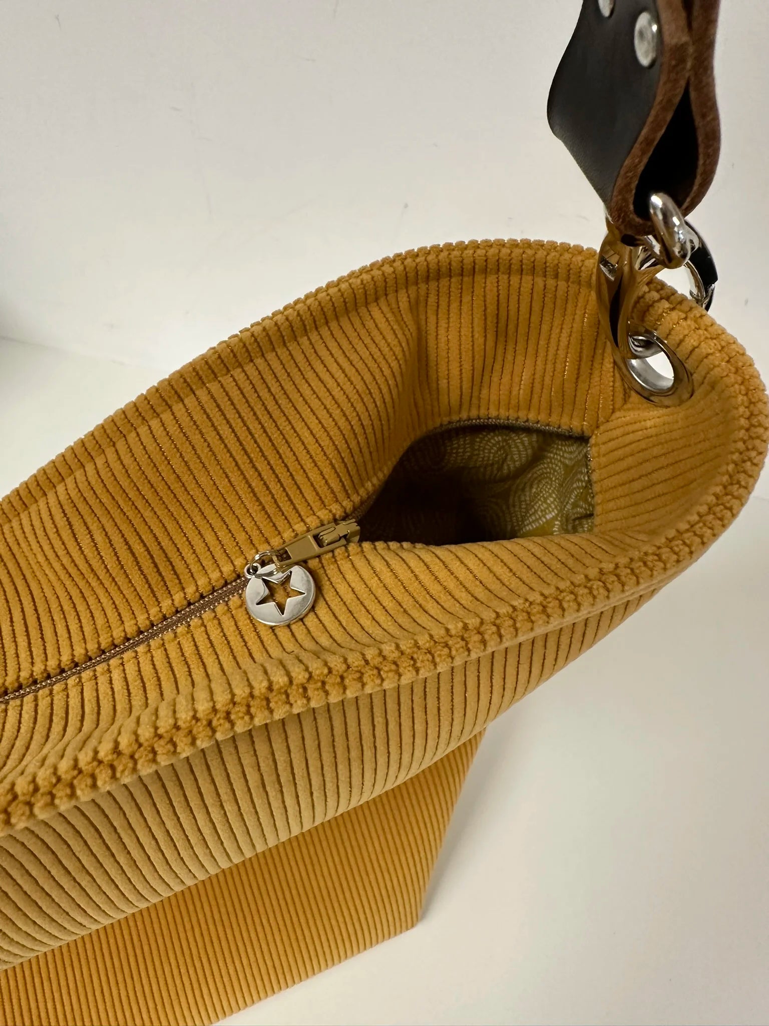 Le sac hobo en velours cotelé jaune moutarde avec fermeture éclair.