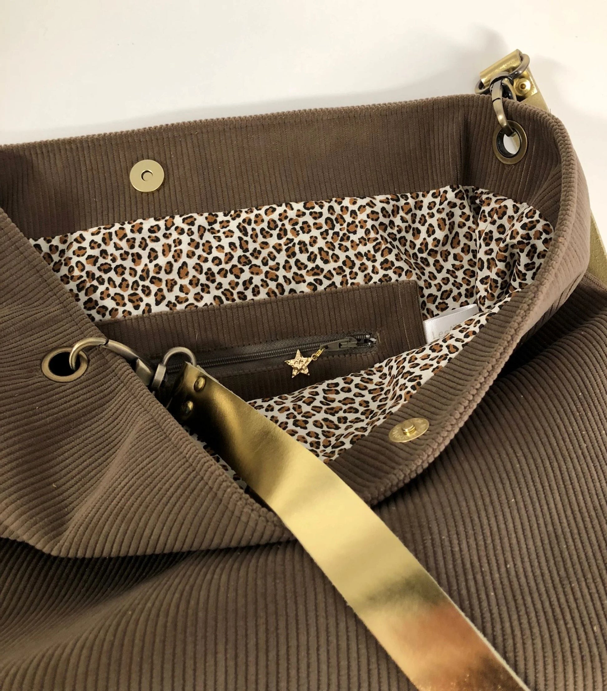 La poche intérieure zippée du sac hobo en velours côtelé marron chamois et son anse en cuir doré