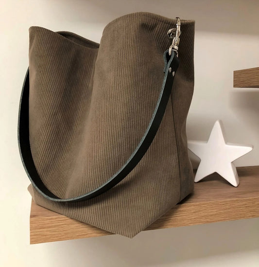 Le sac hobo en velours cotelé marron chamois et son anse en cuir noir amovible.