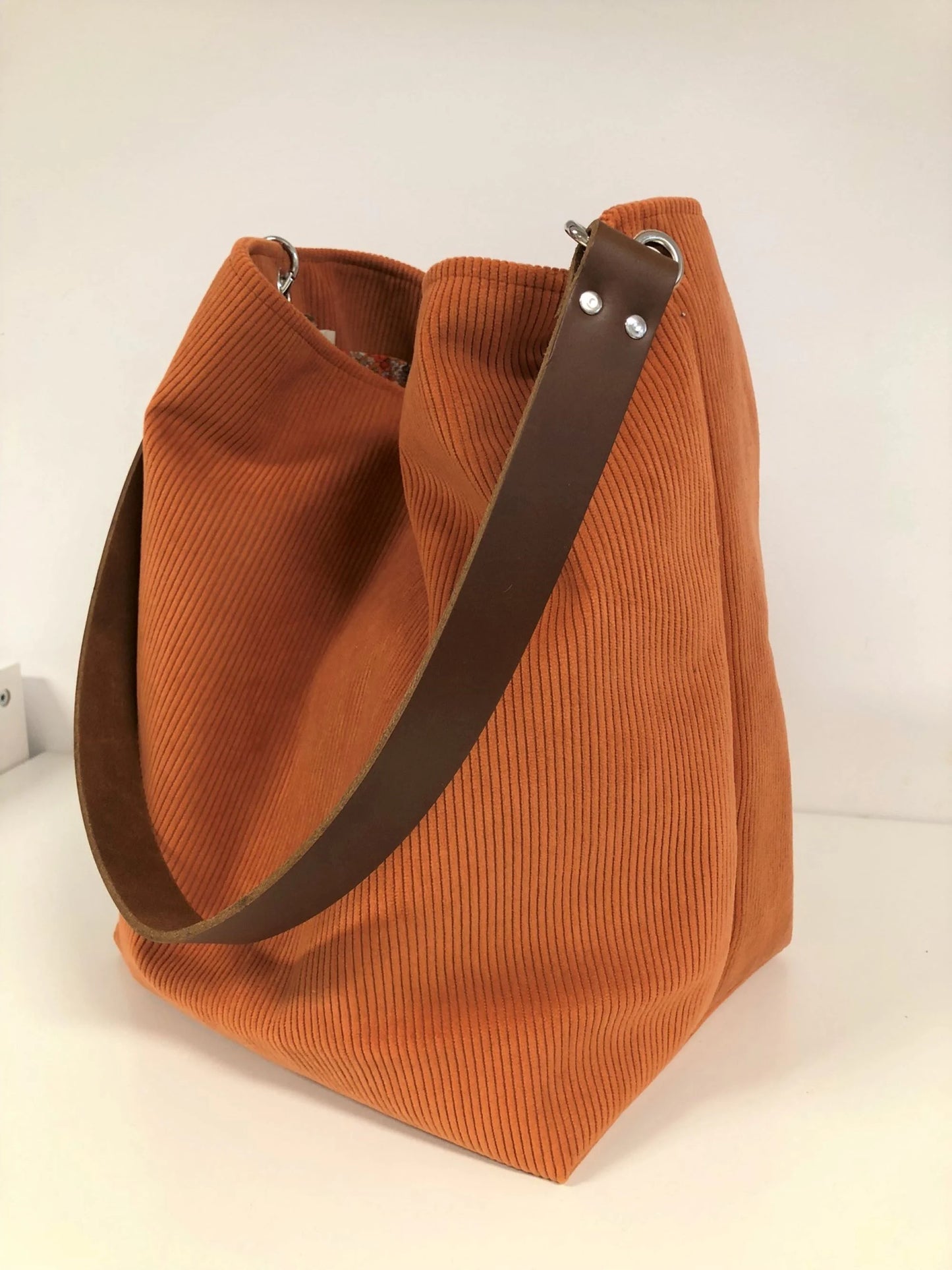 Le sac hobo en velours cotelé orange et son anse en cuir amovible.