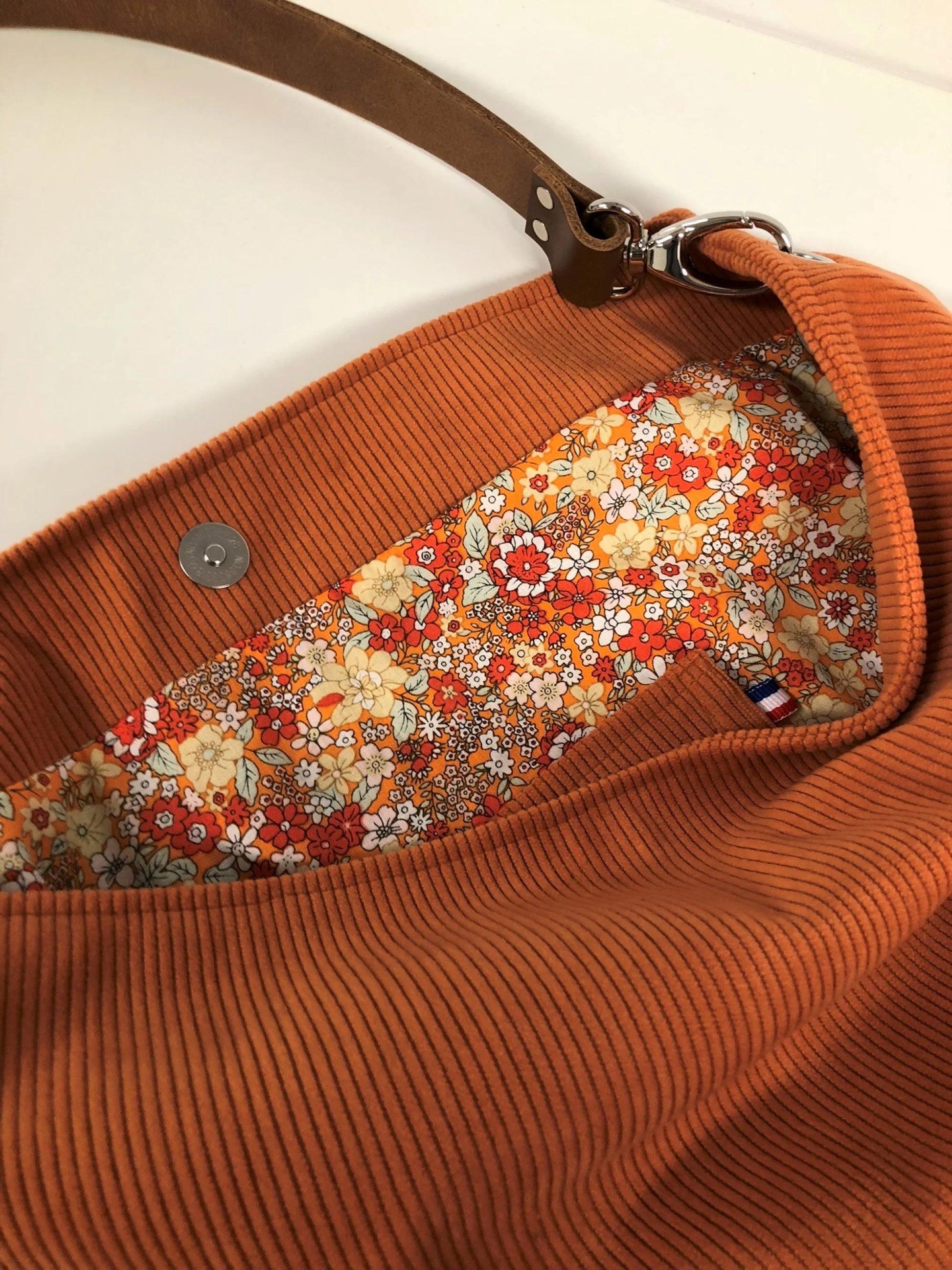 La poche plaquée intérieure du sac hobo en velours cotelé orange.