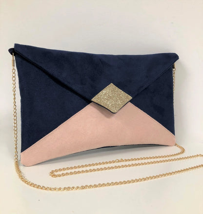 Le sac pochette Isa bleu marine et beige nude à paillettes dorées, avec chainette amovible, sur fond neutre.