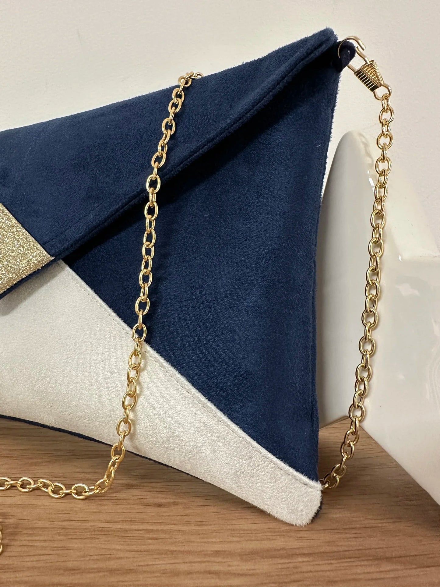 La chainette dorée amovible du sac pochette Isa bleu marine et blanc à paillettes dorées,.