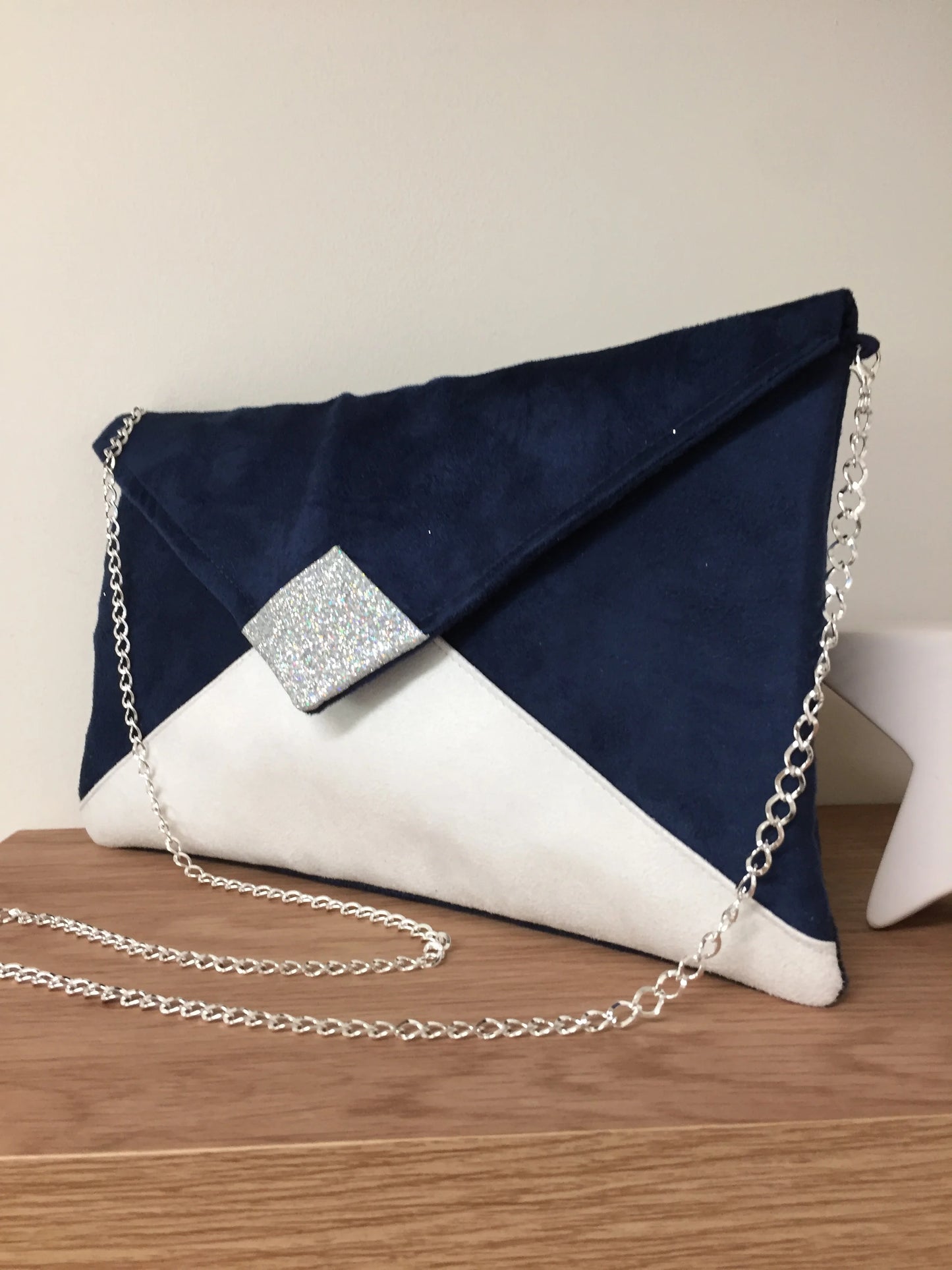 Le sac pochette Isa bleu marine et blanc à paillettes argentées, avec chainette amovible.