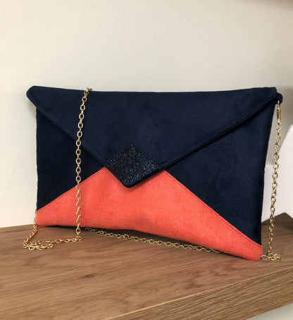 Le sac pochette Isa bleu marine et corail à paillettes bleu marine, avec chainette amovible.