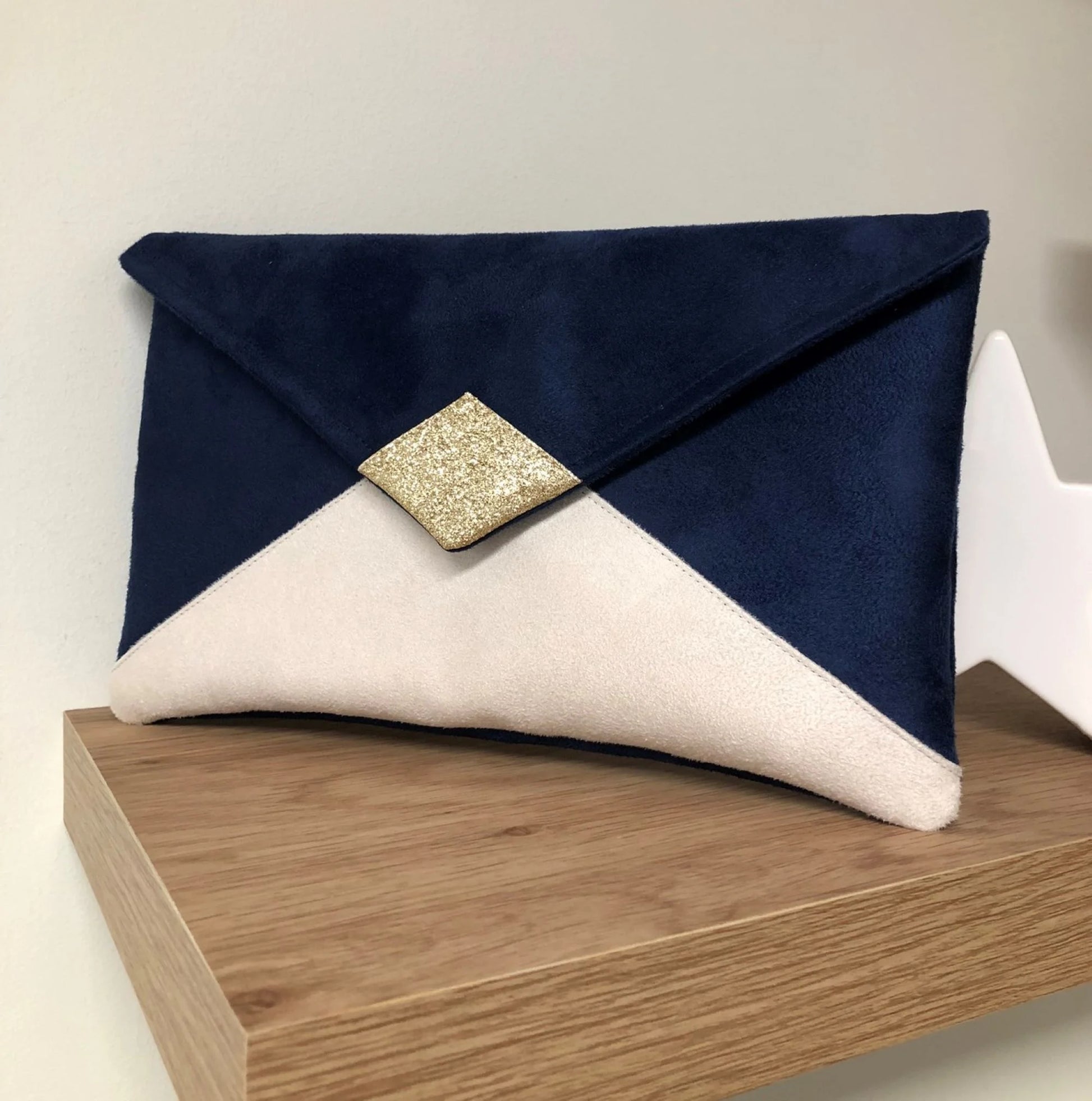 Le sac pochette Isa bleu marine et écru à paillettes dorées, sans chainette.