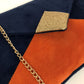 Vue détaillée du sac pochette Isa bleu marine et orange à paillettes dorées, avec chainette amovible.