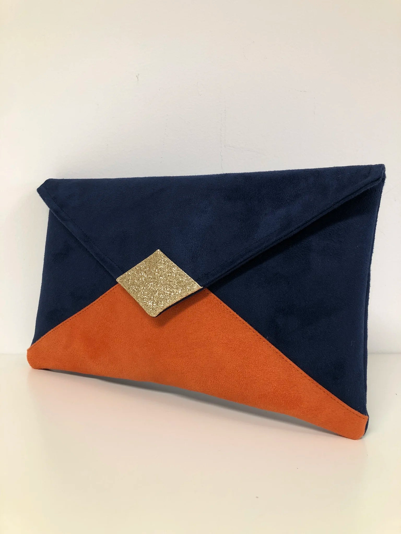 le sac pochette Isa bleu marine et orange à paillettes dorées, sans chainette amovible.