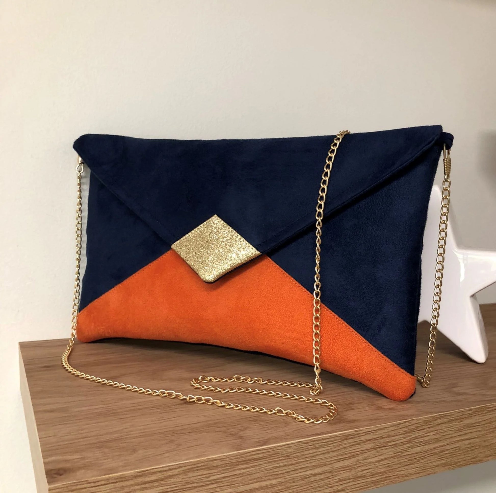 le sac pochette Isa bleu marine et orange à paillettes dorées, avec chainette amovible.