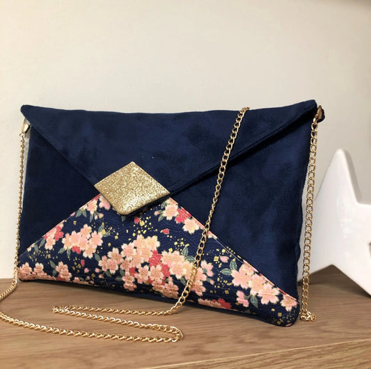 Le sac pochette Isa bleu marine à fleurs de cerisier et paillettes dorées, avec sa chainette dorée amovible.