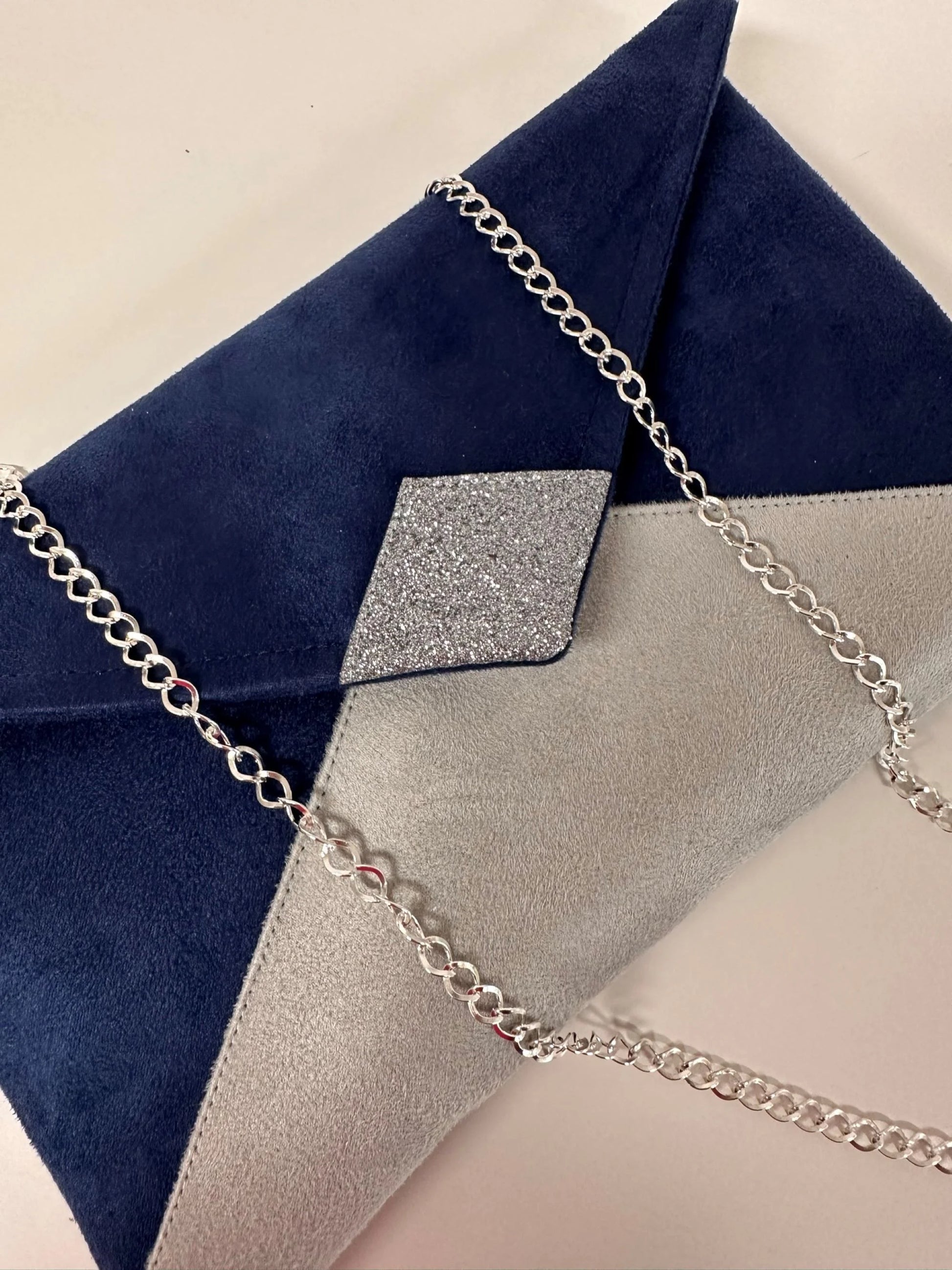 Vue détaillée du sac pochette Isa bleu marine et gris à paillettes argentées, avec sa chainette amovible.