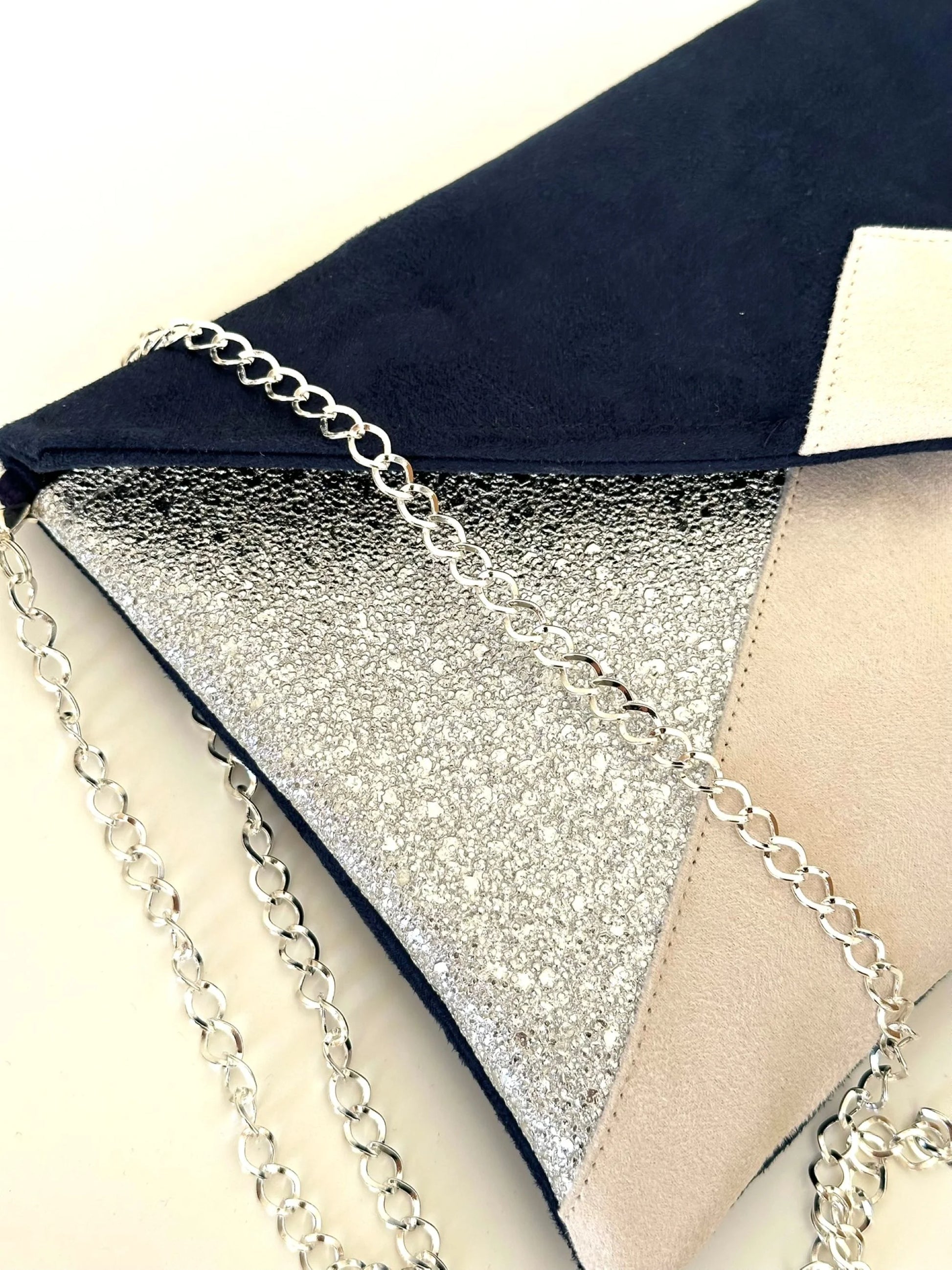 Vue latérale du sac pochette Isa bleu marine, ivoire et argenté.