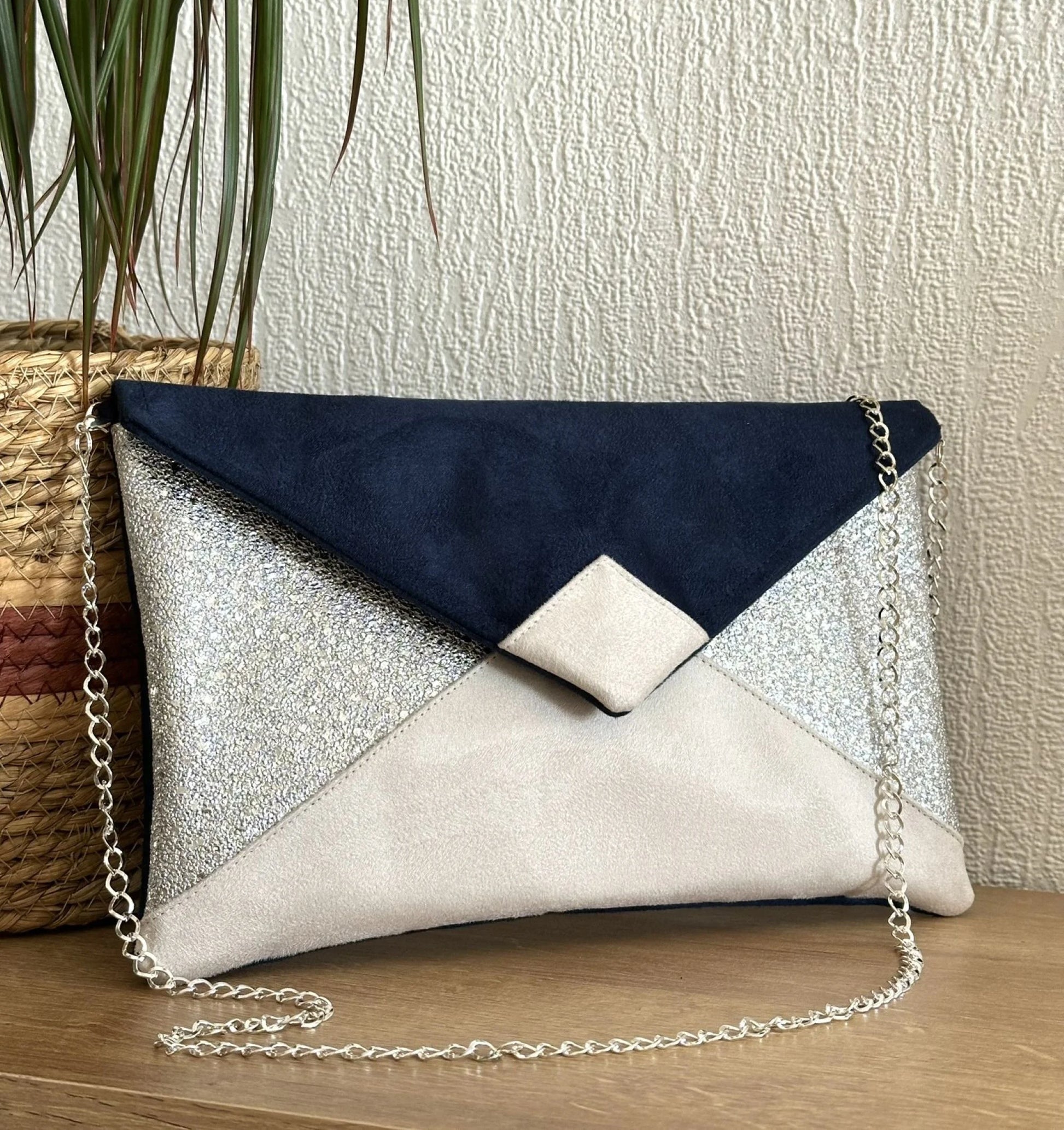 Le sac pochette Isa bleu marine, ivoire et argenté avec sa chainette amovible.