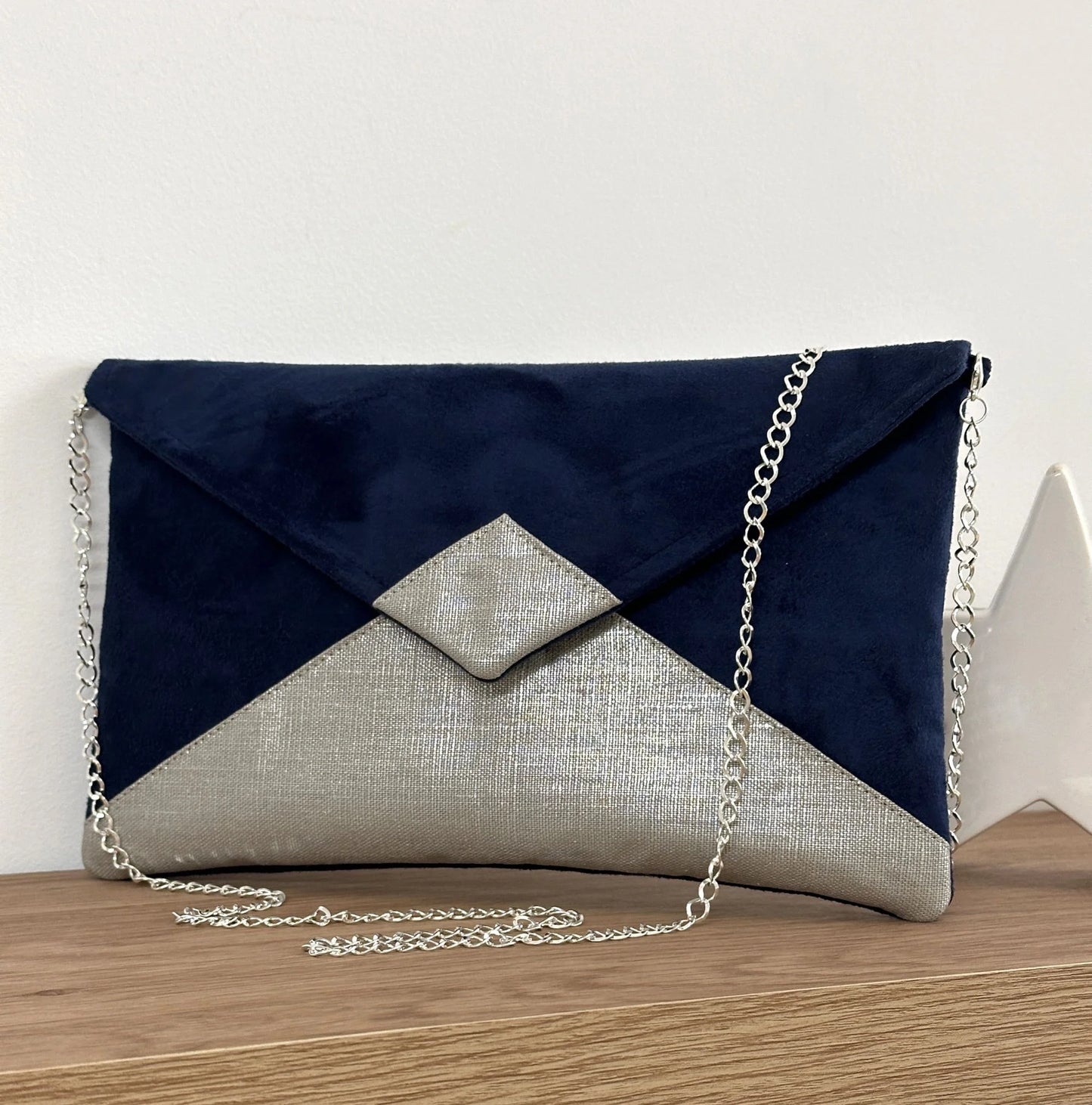 Le sac pochette Isa bleu marine en lin argenté, présenté avec chainette argentée amovible.