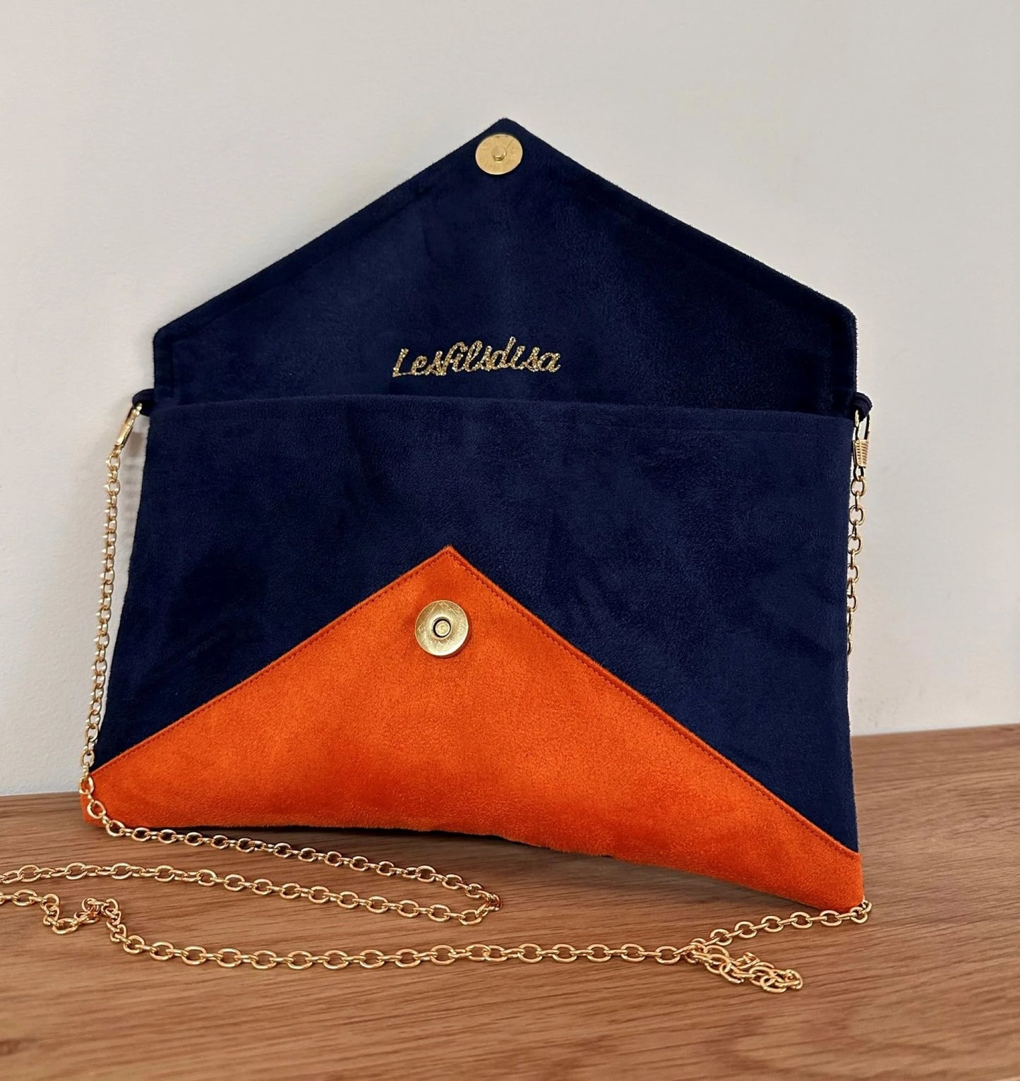 Le sac pochette Isa bleu marine et orange à paillettes, avec chainette dorée, ouvert.