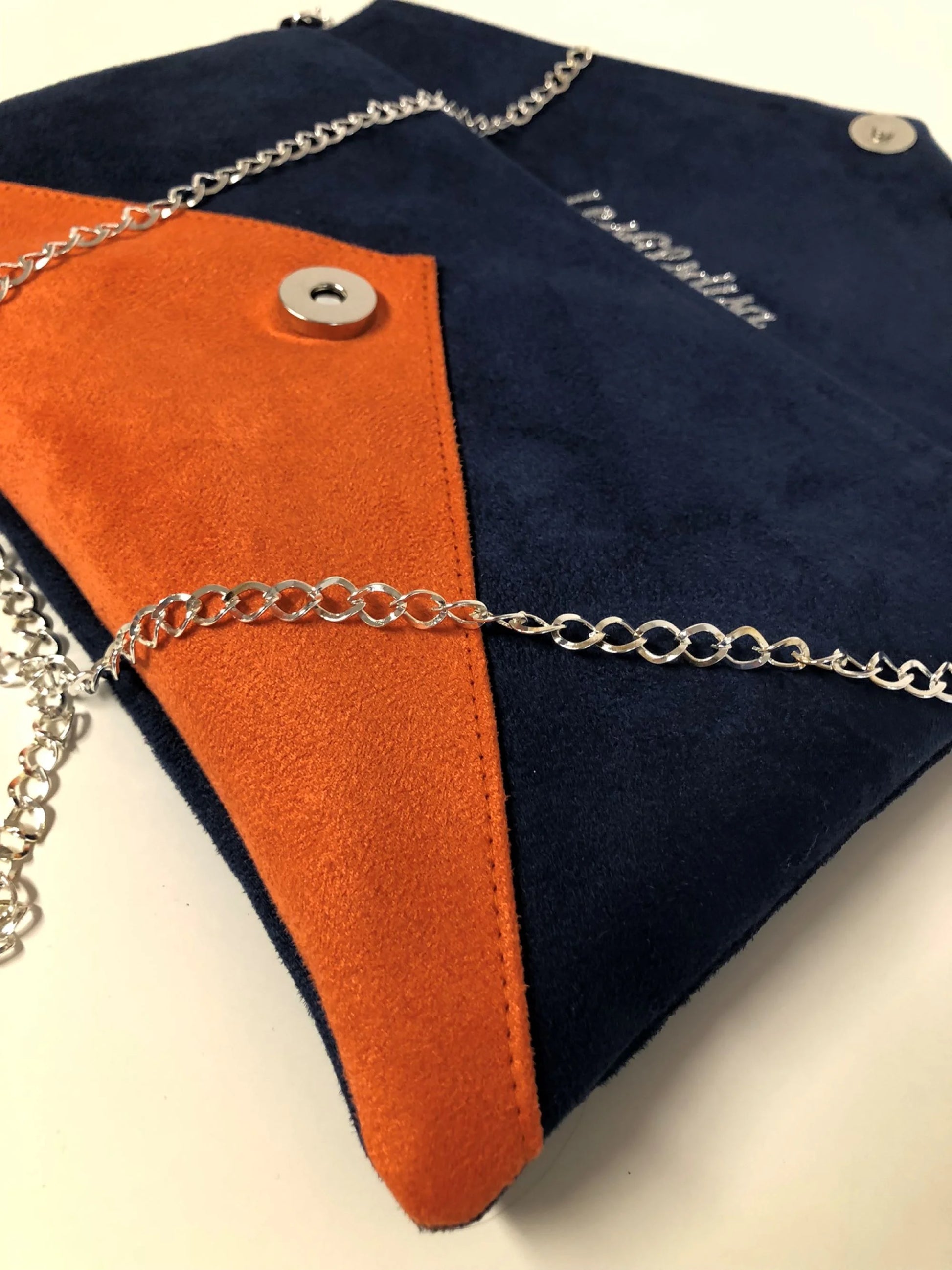 Vue détaillée du sac pochette Isa bleu marine et orange à paillettes argentées, avec chainette amovible.