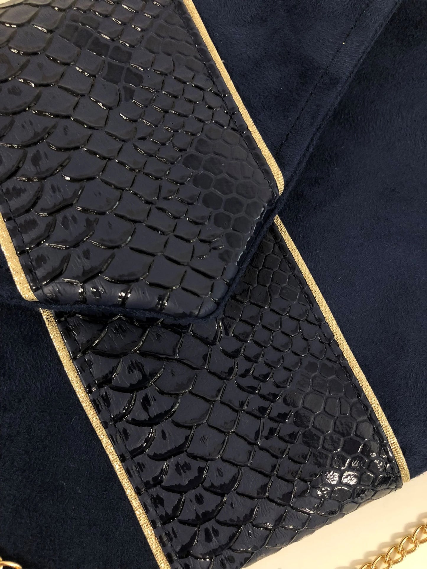 Vue détaillée du rabat du sac pochette Isa bleu marine reptile à liseré doré.