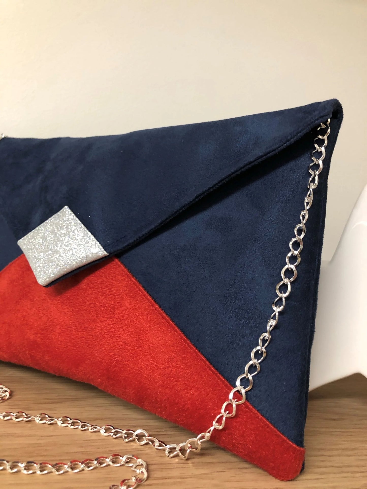 Le sac pochette Isa bleu marine et rouge à paillettes argentées avec chainette amovible.