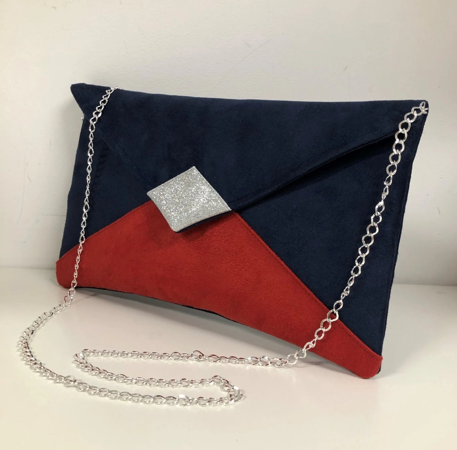 Le sac pochette Isa bleu marine et rouge à paillettes argentées avec chainette argentée.