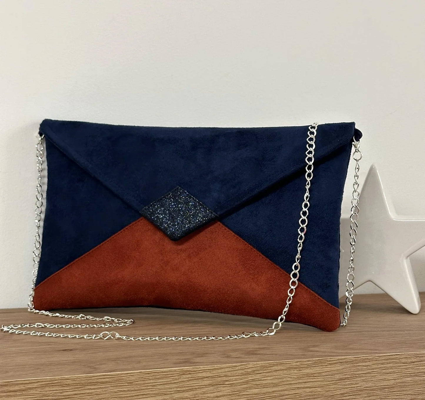 Le sac pochette Isa bleu marine et terracotta à paillettes, avec chainette argentée amovible