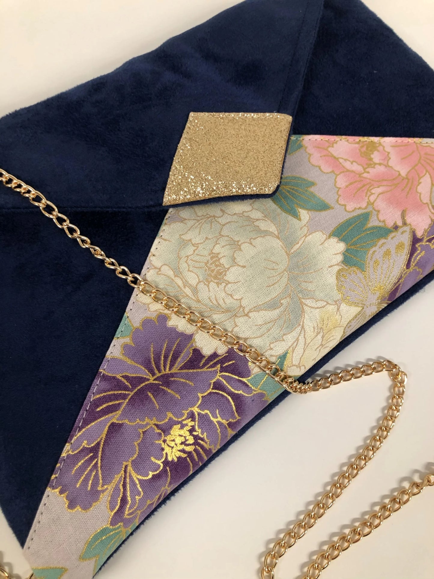 Vue détaillée du sac pochette Isa bleu marine en tissu japonais à fleurs mauve et rose et paillettes dorées.