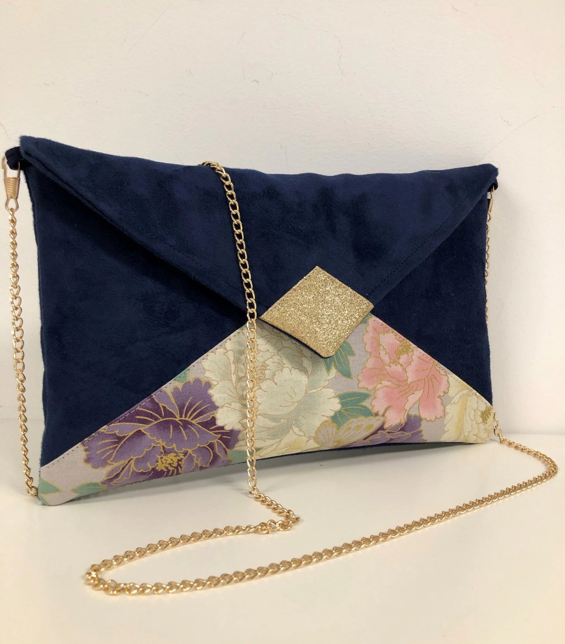 Le sac pochette Isa bleu marine en tissu japonais à fleurs mauve et rose et paillettes dorées.