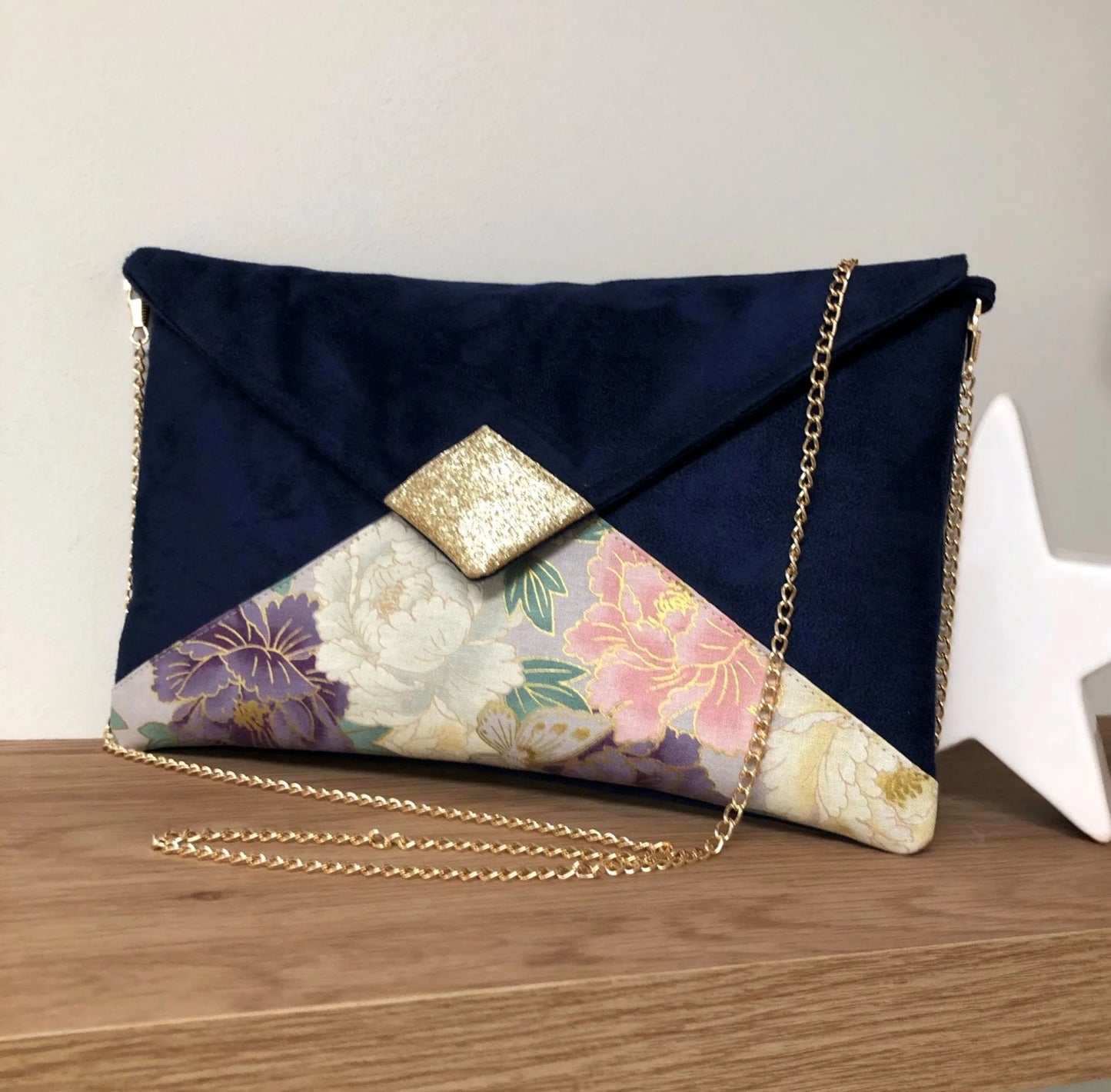 Le sac pochette Isa bleu marine en tissu japonais à fleurs mauve et rose et paillettes dorées, avec chainette amovible.