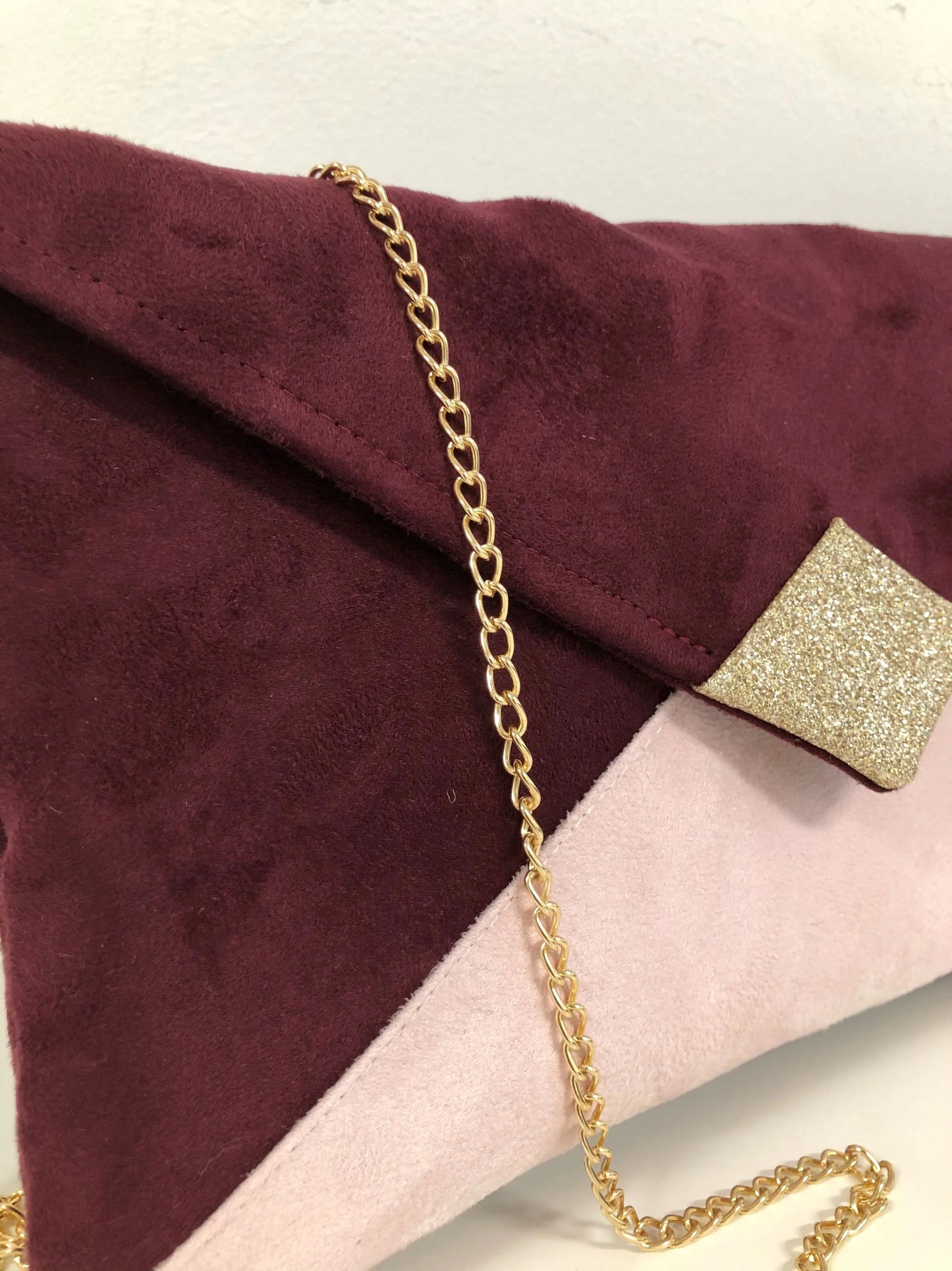 Vue de près du sac pochette Isa bordeaux et rose pâle à paillettes dorées