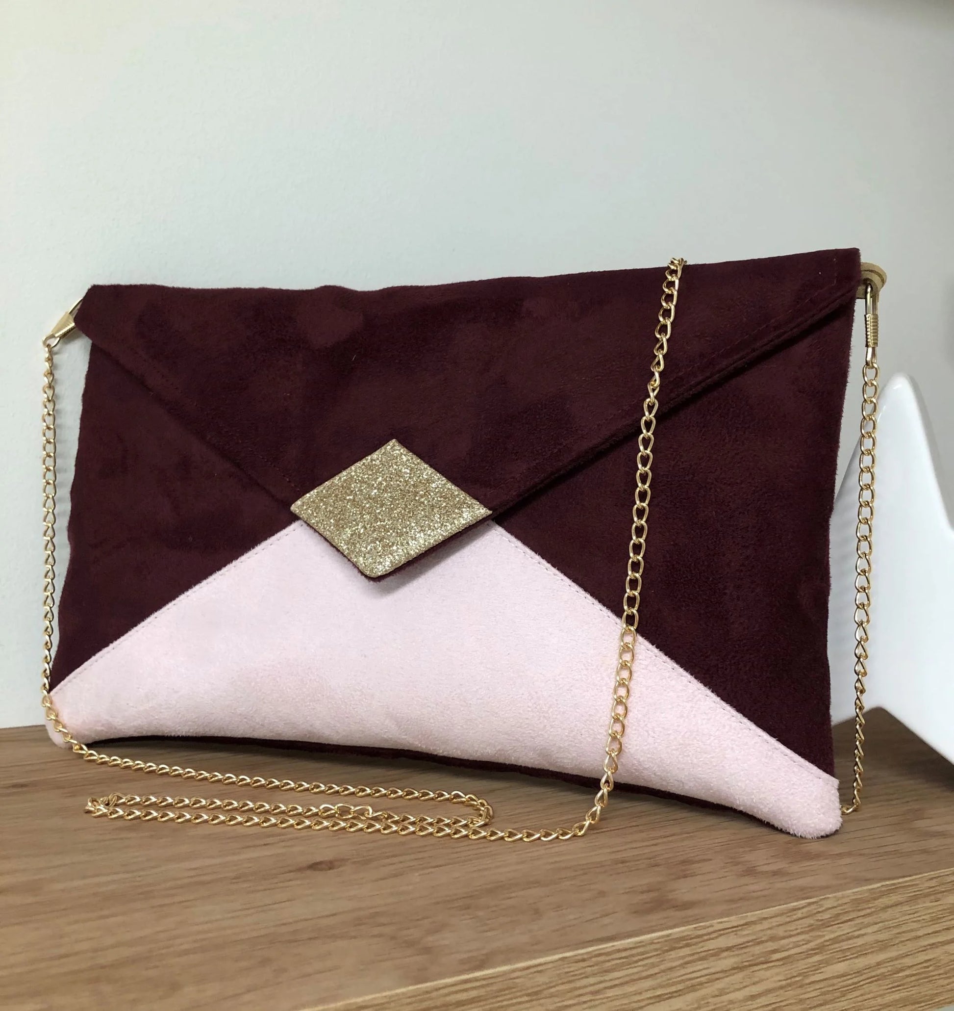Le sac pochette Isa bordeaux et rose pâle à paillettes dorées, avec chainette amovible