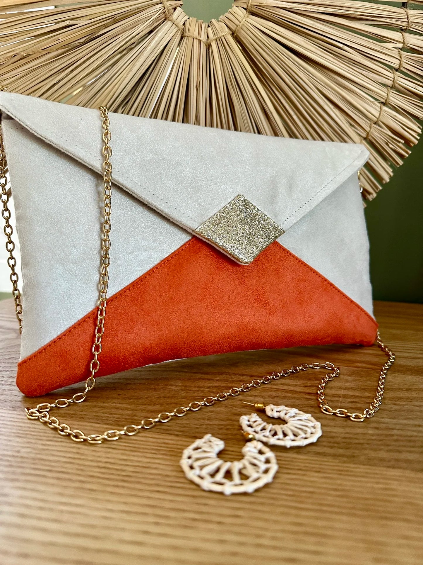 Le sac pochette Isa écru et orange à paillettes dorées, avec chainette amovible.