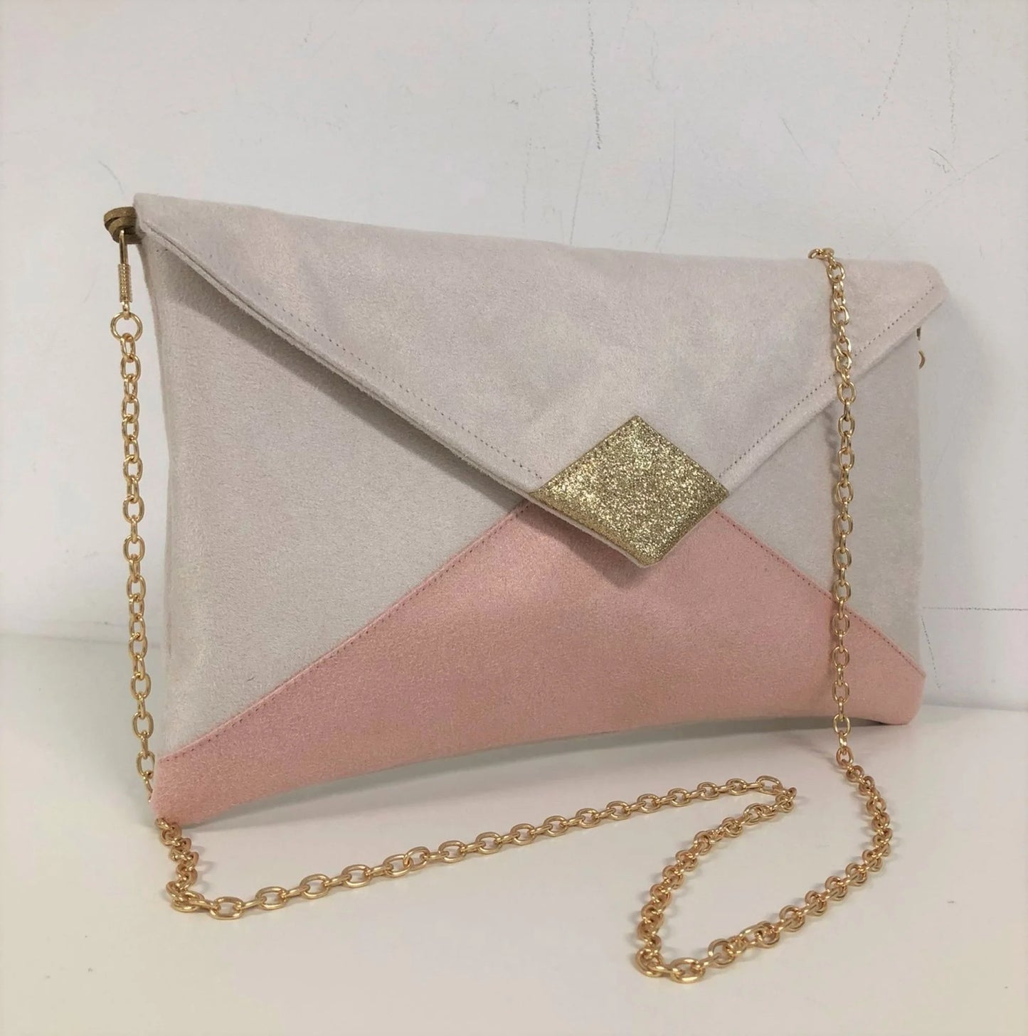 Le sac pochette Isa écru et rose poudré à paillettes dorées avec chainette .