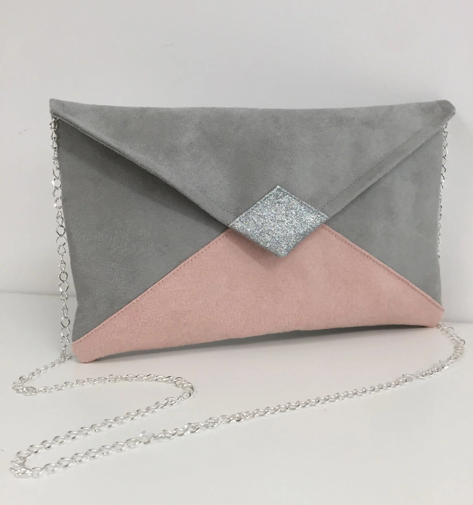Face avant du sac pochette Isa gris clair et rose poudré à paillettes argentées, avec sa chainette amovible.