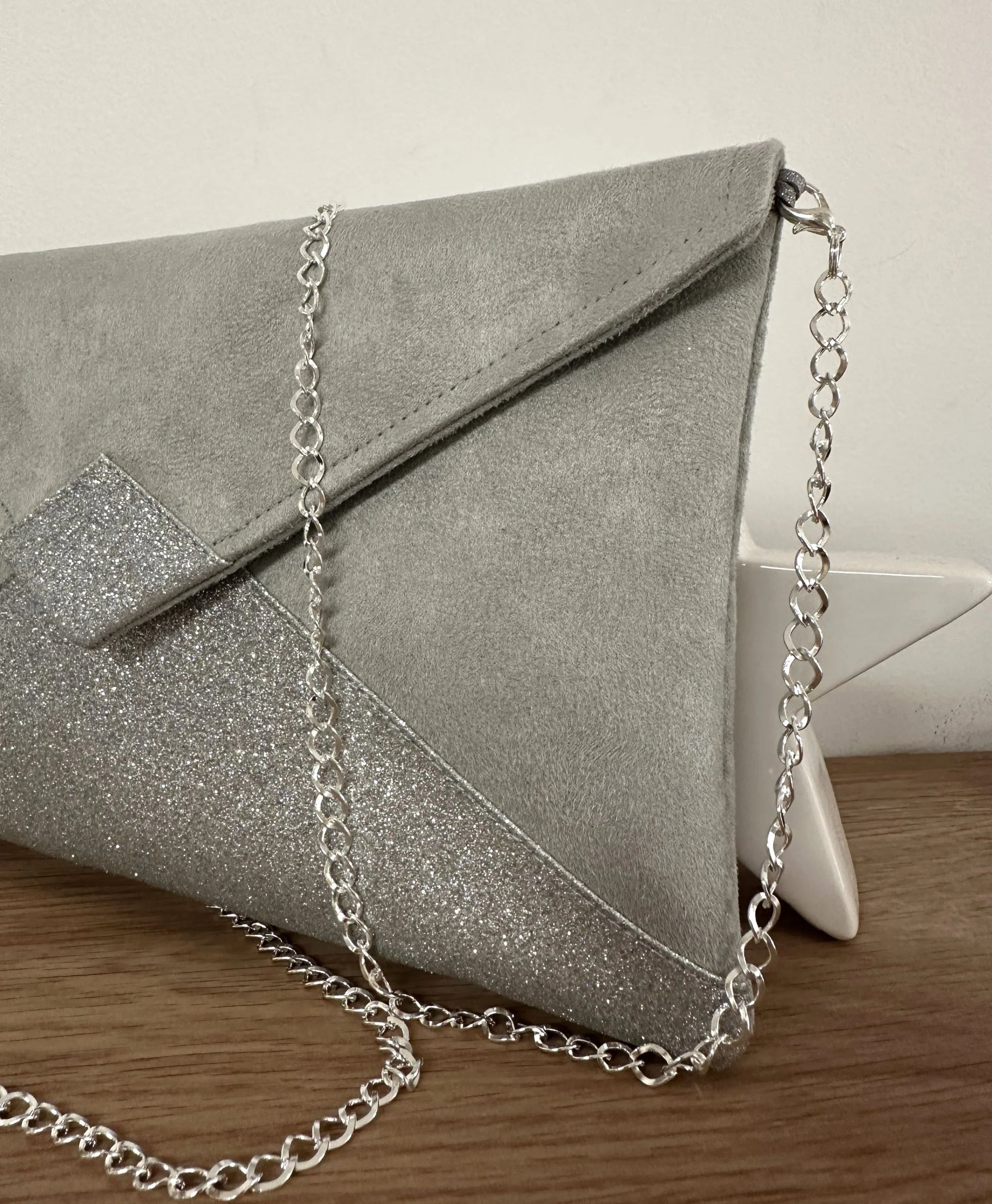Vue détaillée du sac pochette Isa gris perle à paillettes argentées, avec sa chainette.