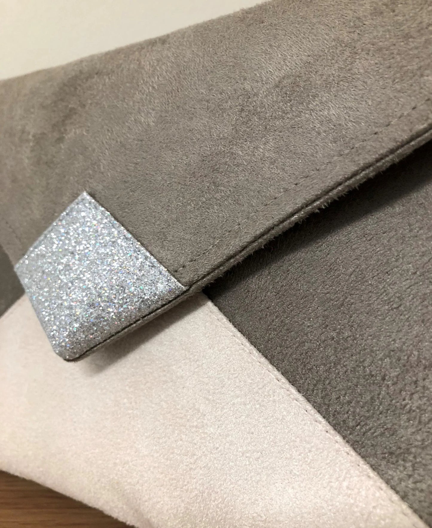 Vue détaillée du sac pochette Isa gris taupe et écru à paillettes argentées.