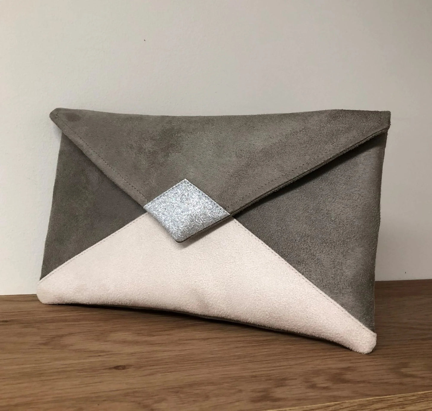 Le sac pochette Isa gris taupe et écru à paillettes argentées, sans chainette amovible.