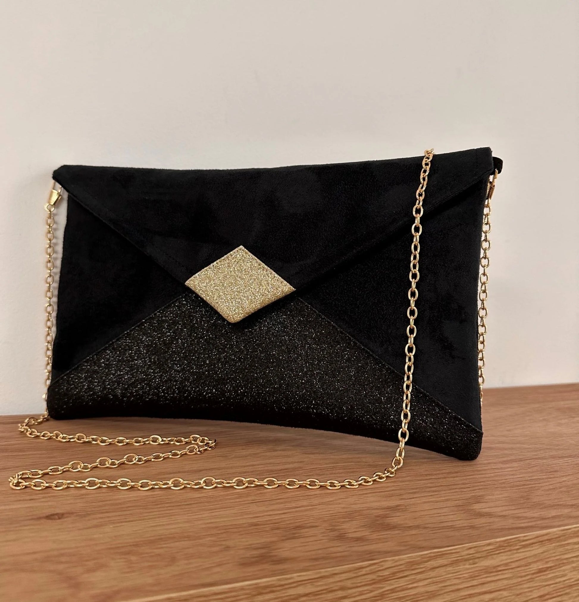 Le sac pochette Isa noir et doré à paillettes, avec sa chainette amovible.