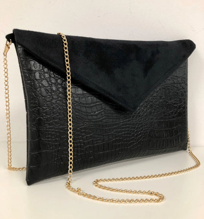 Le sac pochette Isa noir mat aspect reptile, avec chainette dorée.